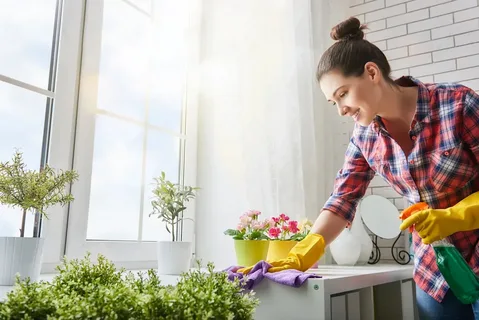 Woman wiping down household furniture during a bright and sunny Spring Cleaning routine